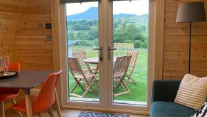 a room with a patio door with a table and chairs at MTB Jumps View Pod in Trawsfynydd