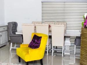 ein gelber Stuhl mit einem lila Kissen neben einem Tisch in der Unterkunft Casa Moderna Frente Alberca 3 min de la Playa Azul Pacifico in Mazatlán