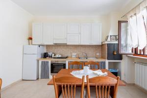 een keuken met een houten tafel en witte kasten bij Villa Rosa by Rentbeat in Montalbano