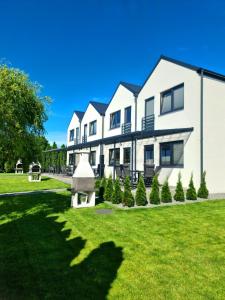 a large white house with a green lawn at Władysławowska 36 - domki i pokoje gościnne in Władysławowo