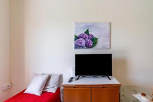 een slaapkamer met een bed met een tv en een schilderij bij Villa Rosa by Rentbeat in Montalbano +19 foto's