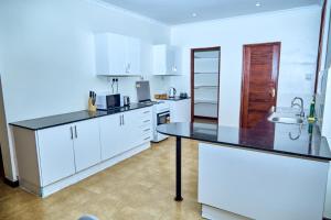 Una cocina con gabinetes blancos y una encimera negra. en Mount Meru View Homestay, en Arusha
