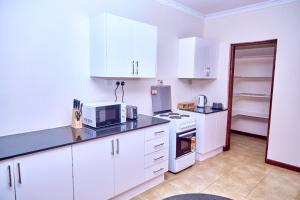 Una cocina con gabinetes blancos, estufa y refrigerador. en Mount Meru View Homestay, en Arusha 5 fotos más