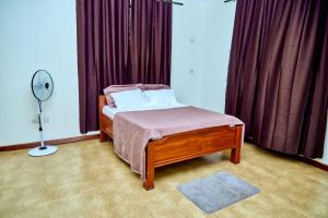 1 dormitorio con cama, ventilador y cortinas en Mount Meru View Homestay, en Arusha