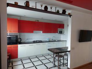 a kitchen with red cabinets and a table in it at Apartment On Pribuzhskaya 2 in Khmelʼnytsʼkyy