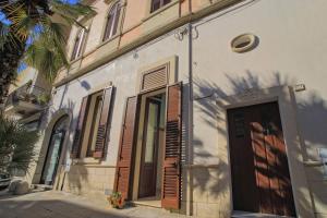 een wit gebouw met een deur en een palmboom bij Casa Orchidea in Tricase