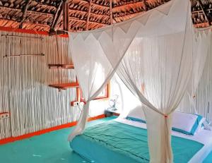 a bed with a canopy in a room at CocoKabanasRote in Nembrala