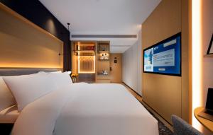 a bedroom with a large white bed and a tv at Park Inn by Radisson, Nanchang Honggutan Wanda Plaza Twin Towers in Nanchang