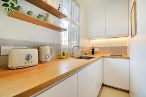 Una cocina con gabinetes blancos y una encimera de madera. en Lovely Studio, en Boulogne-Billancourt
