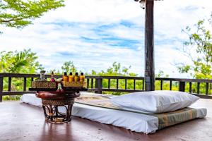 un letto appoggiato sopra un portico con un tavolo di OMD Wellness Resort at Bungasari a Ban Sap Bon