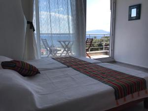 a bed in a room with a large window at Assos Gardenya Butik Otel in Ayvacık