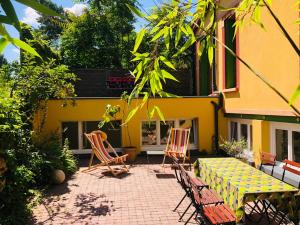 a patio with two chairs and a table and a yellow building at Charmante villa aux portes de Paris in Issy-les-Moulineaux