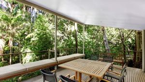 a balcony with a table and chairs and trees at Sand & Sea - Pearl Beach With Pool in Pearl Beach