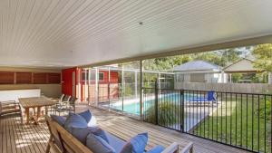 a deck with a couch and a table and a pool at Sand & Sea - Pearl Beach With Pool in Pearl Beach