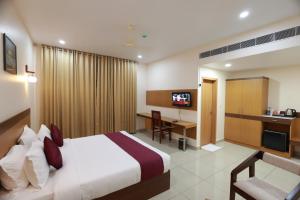 a hotel room with a bed and a desk at Hotel Floral Palace in Kottayam
