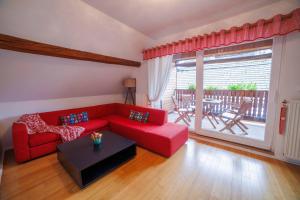 a living room with a red couch and a table at Hiša na Dovjem in Mojstrana