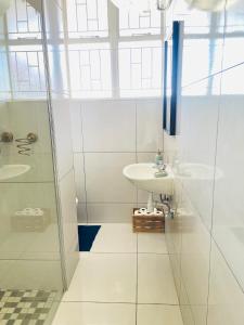 a white bathroom with a sink and a shower at Villa Saarchi Apartments in Windhoek