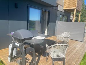a grill on a deck with chairs and a table at Arendalsuka Vacation Norway in Froland Verk
