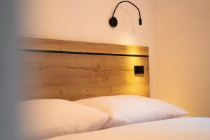 a bedroom with a wooden headboard and a white bed at PÚŠŤ rekreačné stredisko in Prievidza