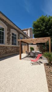 un patio con pergolato in legno, tavolo e sedie. di La Maison D'Olivier a Mesnard-la-Barotière