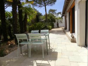 a patio with four chairs and a table on a sidewalk at Les palmes de Jade in Saint-Brevin-les-Pins