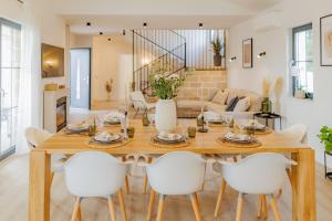 a dining room and living room with a wooden table and white chairs at Luxury Villa Oliva Oliana heated pool 32m2 in Vrsi
