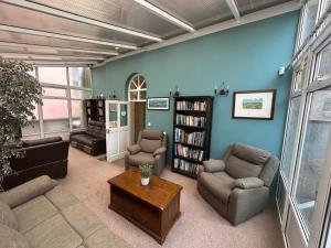 a living room with a couch and chairs and a book shelf at Long Quay House in Kinsale