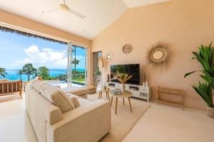 a living room with a couch and a tv at Palm Tree Seaview Villa in Koh Samui 