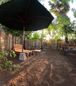 a bench and an umbrella in a yard at C U Hostel in Trincomalee