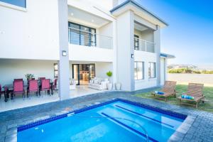 a villa with a swimming pool and a house at Golfer's Dream Haven in Knysna