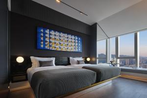 a bedroom with two beds and a painting on the wall at ISEYA Panoramic Hotel Chongqing Jiefangbei Raffles Plaza in Chongqing