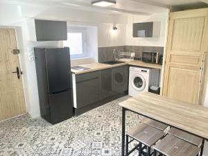 a kitchen with a black refrigerator and a table at Le Ptit Rupt in Rupt-sur-Moselle