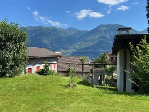una casa con un giardino verde con montagne sullo sfondo di Muralto - Locarno: Miramonti Apt.5 a Muralto