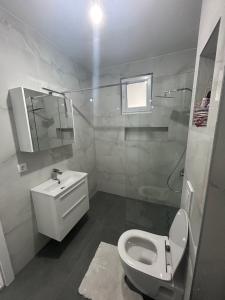 a white bathroom with a toilet and a sink at Sweet Holiday in Mostar