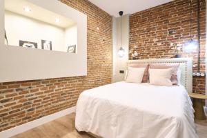 a bedroom with a brick wall and a white bed at El capricho II en la Plaza Mayor centro Salamanca by keyhom in Salamanca