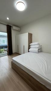 班达拉朗西ไนซ์สเตย์ เฮาส์ แอทคลองสาม รังสิต คลองหลวง ปทุมธานี Nice Stay House at Khlong Sam - Rangsit - Khlong Luang - Phathumthani的卧室里有一张大床，床单和枕头都是白色的