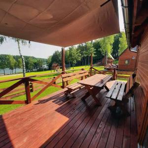 a wooden deck with benches and a picnic table at Kaszubskie Domki Nad Jeziorem Bluj in Głodowo