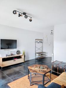 a living room with a table and a tv at L'oasis d'Anatole in Oyonnax +9 photos