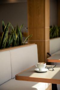 a cup of coffee on a table with a plant at Akti Hotel Kavala in Paleo Tsifliki