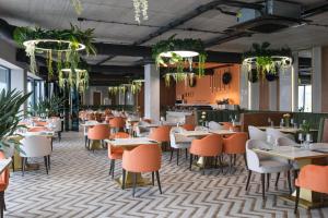 ein Restaurant mit Tischen, Stühlen und Pflanzen in der Unterkunft Laguna Beskidów Resort - Apartament B35 in Zarzecze