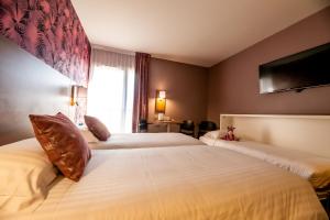a hotel room with two beds and a television at Brit Hotel Eden SPA Honfleur in Honfleur