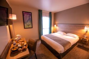 a hotel room with a bed and a table with a tray of food at Brit Hotel Eden SPA Honfleur in Honfleur