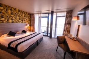 a hotel room with a bed and a large window at Brit Hotel Eden SPA Honfleur in Honfleur