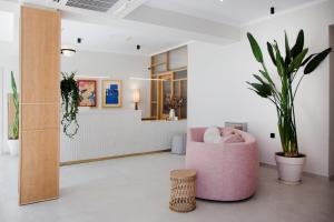 a living room with a pink chair and plants at Akti Hotel Kavala in Paleo Tsifliki