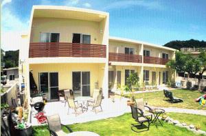 a house with chairs and a table in the yard at Cha Villa in Zamami