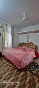 a bedroom with a large bed with a pink blanket at Fam HomeStay in Jorhāt