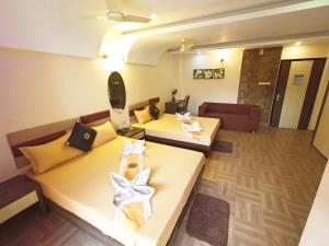 a hotel room with two beds and a couch at The Piku's in Digha