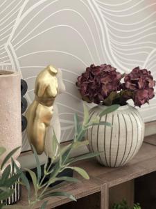 una statua seduta su un tavolo accanto ai fiori di La Strada Central Apartament a Oradea