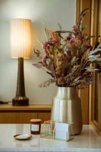 a vase with flowers and a candle on a table at Akti Hotel Kavala in Paleo Tsifliki