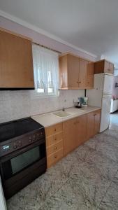 a kitchen with wooden cabinets and a white refrigerator at LY apartment in Kallithea Halkidikis